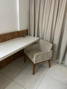 a desk and a chair with a table and a curtain at Ondi Cosmopolitan in Palmas