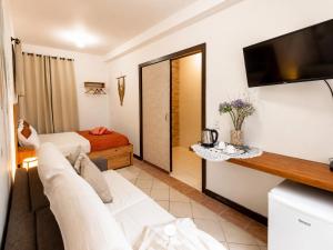a living room with a couch and a tv at Pousada Solar das Pétalas - Florianópolis/SC in Florianópolis