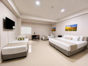 a bedroom with two beds and a flat screen tv at Hotel El Marqués De Manga in Cartagena de Indias