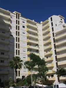 een hoog wit gebouw met palmbomen ervoor bij Apartamento Turf in Alvor +25 foto's