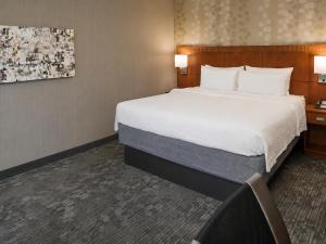 a hotel room with a large bed and a chair at Sonesta Select Seattle Bellevue Redmond in Bellevue