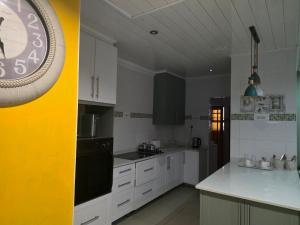 a kitchen with white cabinets and a clock on a wall at RIER Guesthouse in Pretoria