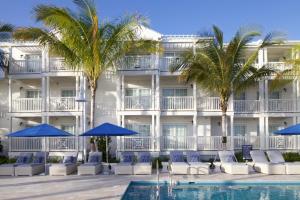 a hotel with a swimming pool and palm trees and blue umbrellas at Oceans Edge Key West in Key West