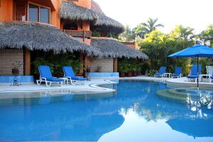 a resort with a swimming pool with chairs and umbrellas at Villa Carolina Boutique Hotel ADULTS ONLY in Zihuatanejo