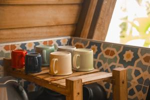 a group of coffee mugs sitting on a wooden shelf at Madre Selva Eco Lodge in Nuquí