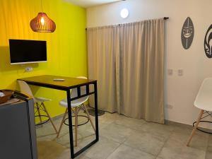 a room with a table and a tv and a yellow wall at Apart Hotel RioSol - Monoambientes in Concepción del Uruguay