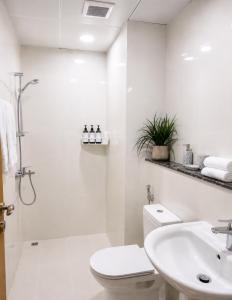 a white bathroom with a toilet and a sink at Travellers Deluxe Apartment in Muscat