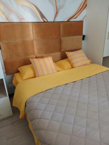 a bedroom with a large bed with yellow and pink pillows at Appartamento Antares Piazza Fontana in Lignano Sabbiadoro