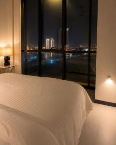 a bedroom with a white bed and a large window at Travellers Deluxe Apartment in Muscat