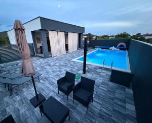 a patio with a pool and chairs and an umbrella at Villa Kleopatra in Međugorje