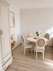 a white dining room with a table and chairs at Mis apartamentai in Mažeikiai