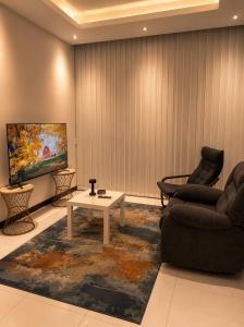 a living room with a couch and a table and a tv at Travellers Deluxe Apartment in Muscat