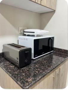 a microwave and a toaster oven sitting on a counter at Travellers Deluxe Apartment in Muscat