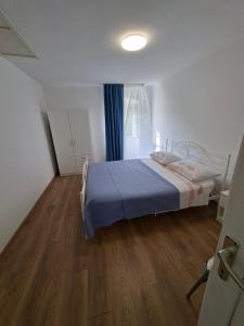 a bedroom with a bed with blue sheets and a wooden floor at Macmalić in Zbičina +5 photos