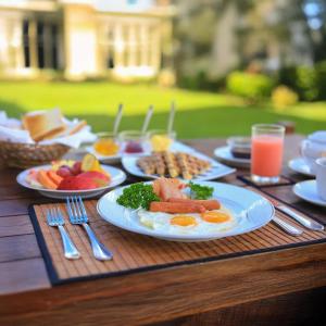 a wooden table with plates of breakfast food on it at Mounts Edge Regency in Mahiyangana
