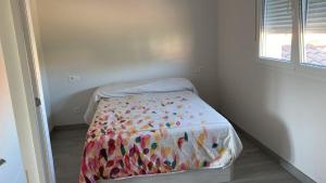 a small bedroom with a bed with a colorful comforter at Villa HEGODEI in A Pobra do Caramiñal +53 photos