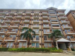 an apartment building with palm trees in front of it at Spacious Studio w Pool, Gym, Smart Lock, Netflix in Puerto Princesa City