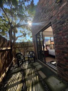 two benches sitting on a patio next to a brick building at Hidden Gem in George +8 photos
