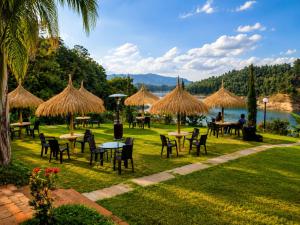 a group of tables and chairs with straw umbrellas at Hotel Pietrasanta Cabañas frente a la Represa Peñol Guatape in Guatapé +134 photos