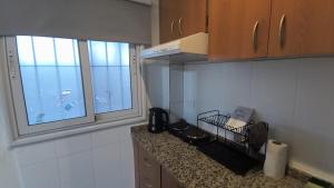 a kitchen with a counter and two windows at Apart Plaza Escobar in Belén de Escobar