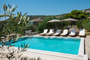a swimming pool with lounge chairs and umbrellas at Villa Rustica - Veslo in Begovići