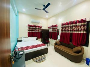 a bedroom with a bed and a couch and red curtains at Hotel Vindhwasni Palace in Sītāmarhi