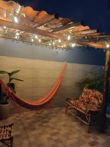 a hammock in a room with a bench and lights at Chalé Montanhez com ar e piscina in Caparaó Velho