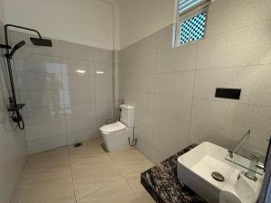 a white bathroom with a toilet and a sink at Cinnamon Ridge Unawatuna in Unawatuna