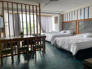 a bedroom with two beds and a desk and a table at Hotel Cristian in Puyo