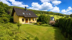 a yellow house in the middle of a green field at Sluneční stráň - dům pro 9 osob in Dolni Dvur