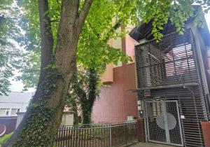a building with a fence next to a tree at Apartament Merkury in Koszalin
