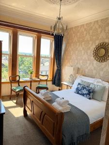 a bedroom with a bed with two chairs and windows at Castle Walk Bed & Breakfast in Stirling