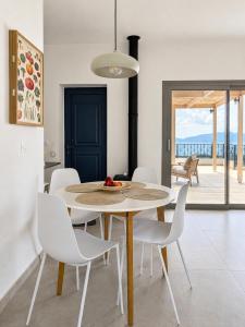 a dining room with a table and white chairs at Trigono Suites - Primavera 