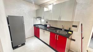 a small kitchen with a sink and red cabinets at Appartement Agadir Tilila 1 pour couples mariés et familles in Agadir