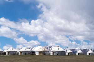 a row of white domed buildings with snow covered mountains at Yurt Camp "Sary-Bulun" at Song-Kul Lake, Naryn Сон-Куль in Song-Kul