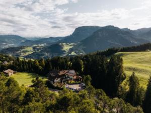 a house on a hill with mountains in the background at Hotel Wiesl in Collepietra