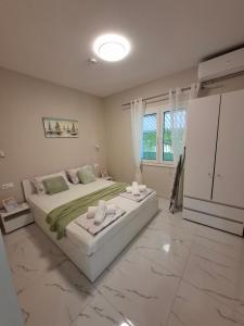 a large white bedroom with a large bed and a window at Zoya's house in Nea Kallikrateia
