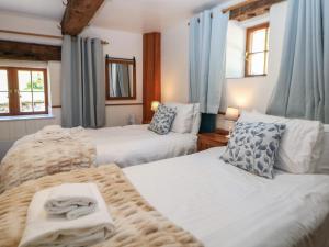 two beds in a bedroom with blue curtains and towels at Slade Cottage in Ashbourne