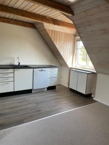an attic kitchen with white cabinets and a window at Vestergård Gæstehus in Varde +27 photos
