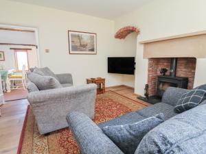 a living room with couches and a fireplace at 1 Fountain Cottages in Tarporley