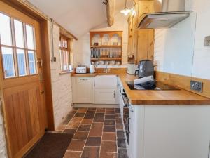 a kitchen with wooden cabinets and a counter top at 1 Fountain Cottages in Tarporley