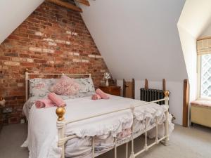 a bedroom with a bed with pink pillows and a brick wall at 1 Fountain Cottages in Tarporley