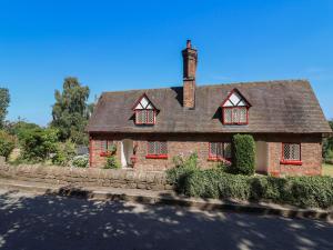 a red brick house with a chimney on a street at 1 Fountain Cottages in Tarporley