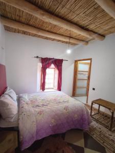 a bedroom with a bed with a purple comforter and a window at Hostel amodou in Tinerhir