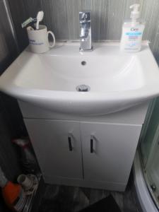 a white bathroom sink with two cups on it at Nad's Guest house in Motherwell +21 photos