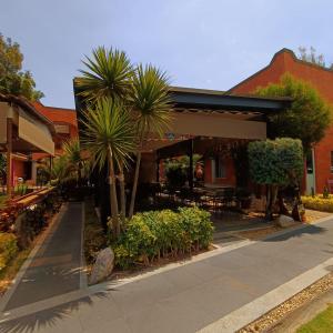 a restaurant with palm trees in front of a building at La Huerta golf & hotel in Cholula