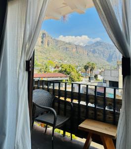a balcony with a table and chairs and mountains at Sierra Central By Chic Hotel Group in Tepoztlán