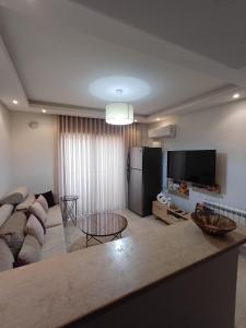 a living room with a couch and a tv at Le charment in Sukrah