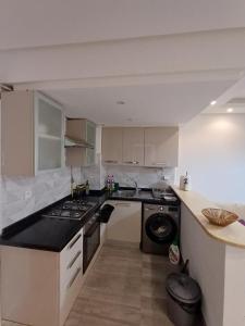 a kitchen with white cabinets and a black counter top at Le charment in Sukrah