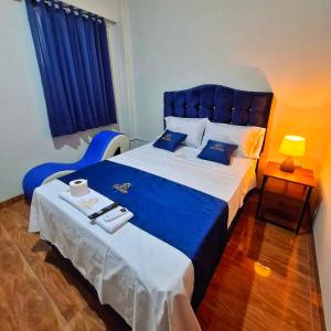 a bedroom with a large bed with a blue headboard at Delcor Suite in Piura